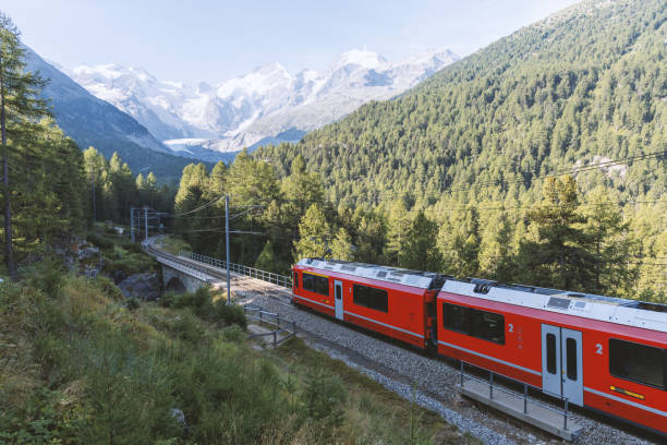 istock Red Train Passing Through Alpine Landscape with Snow-Capped Peaks 2168980141