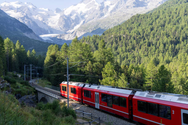 istock Red Train Passing Through Alpine Landscape with Snow-Capped Peaks 2168980143