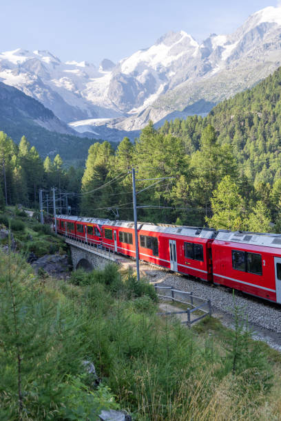 istock Red Train Passing Through Alpine Landscape with Snow-Capped Peaks 2168980165