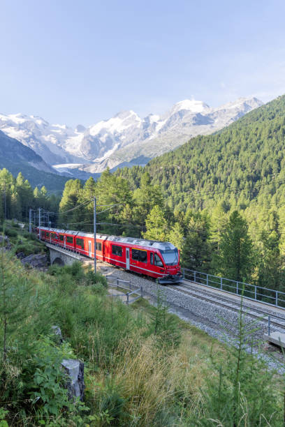 istock Red Train Passing Through Alpine Landscape with Snow-Capped Peaks 2168980208