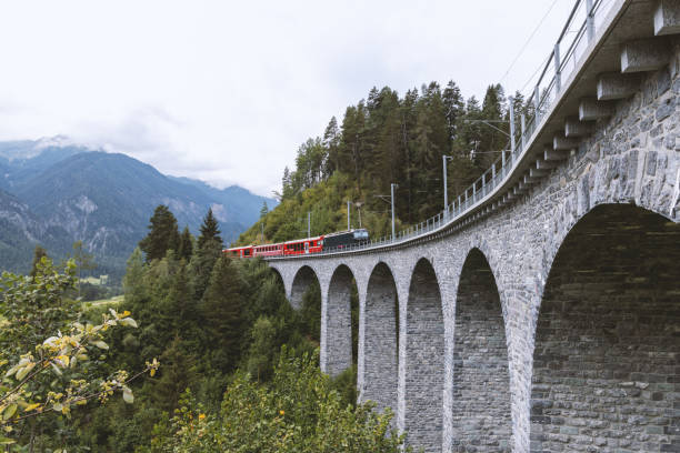 istock Red Train Crossing a Historic Stone Viaduct in the Mountains 2168980496