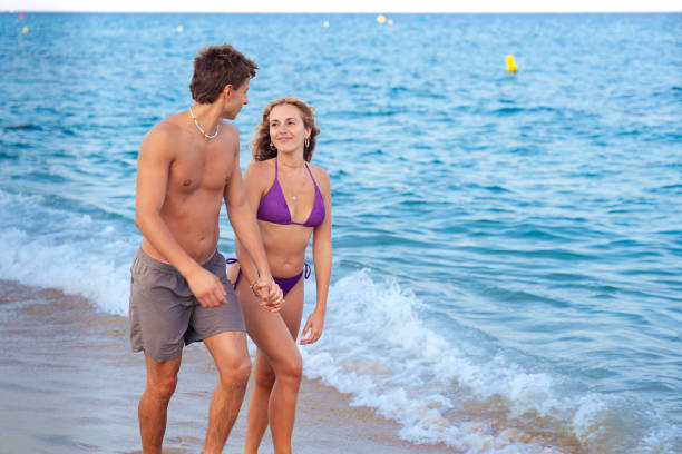 istock Happy young couple walking together on beach 2168980775
