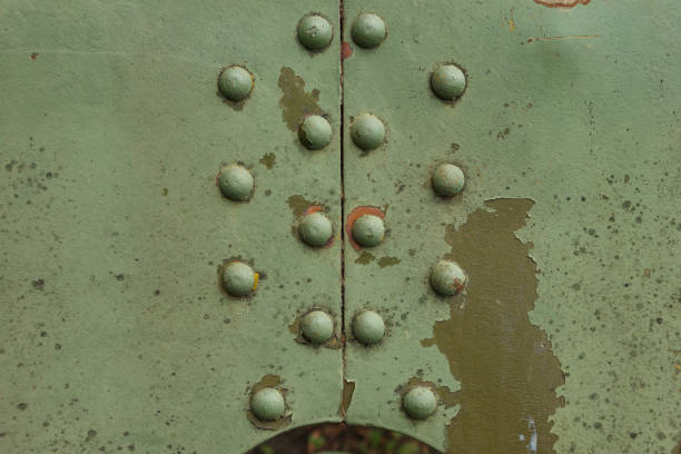 Details artillery gun. Camouflage surface with exfoliated paint and rivets on the armor. Military equipment background. Close-up