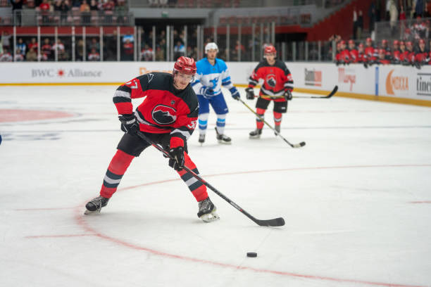Ice Hockey Player Handling the Puck A red team ice hockey player is skillfully handling the puck during a game, with opponents and teammates visible in the background. red hockey jersey stock pictures, royalty-free photos & images