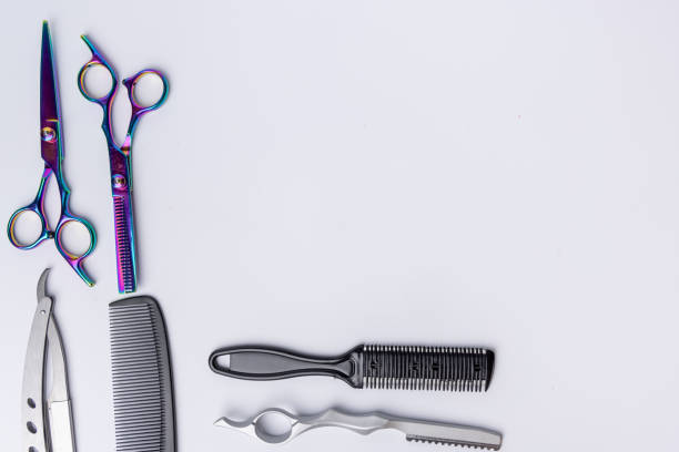 A top-down view of professional barber tools neatly arranged on the left and bottom of a white background. Perfect for showcasing grooming essentials and barbering equipment.
