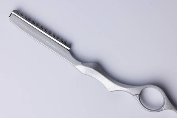A top-down view of a detailed barber’s precision razor set against a white background. The razor is centrally positioned, highlighting its sleek design and sharp blade, ideal for grooming and shaving