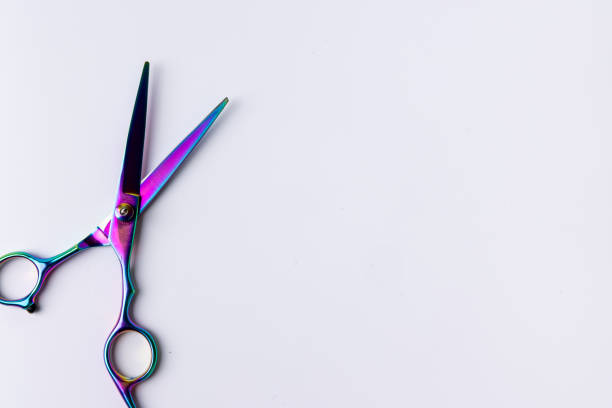 A top-down view of open scissors placed on a clean, white background. The sharp blades and handles are prominently featured on the left side of the image, emphasizing precision and functionality
