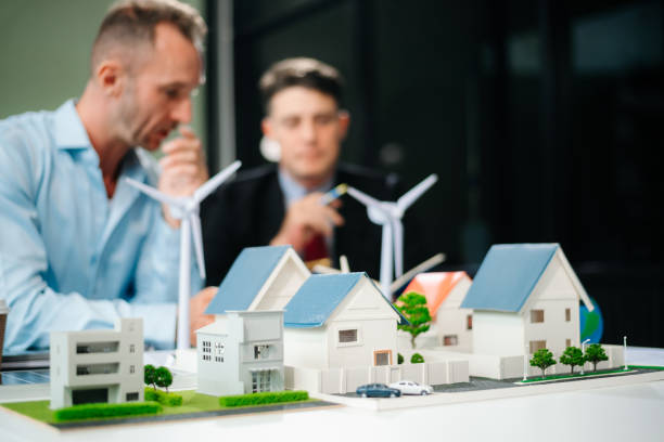 istock Experts collaborate on renewable energy solutions with house models, wind turbines, and solar panels, emphasizing green design 2168992298