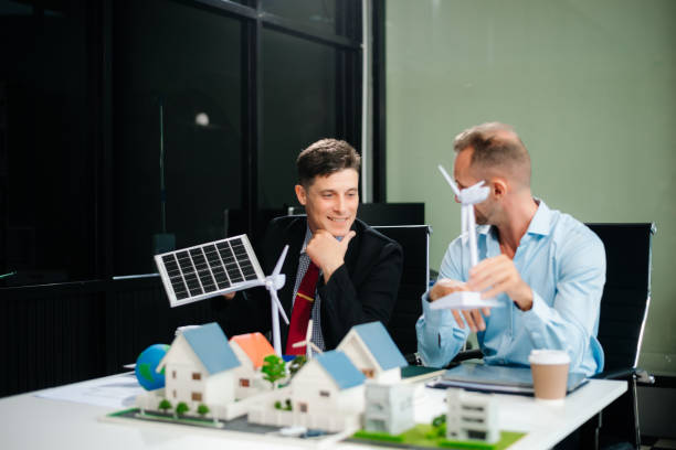 istock Experts collaborate on renewable energy solutions with house models, wind turbines, and solar panels, emphasizing green design 2168992306