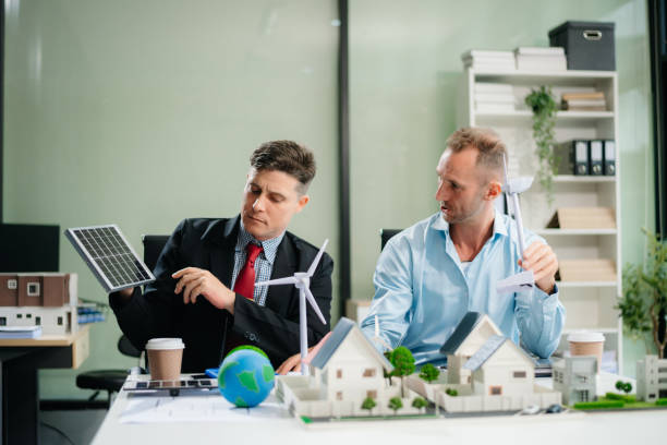 istock Experts collaborate on renewable energy solutions with house models, wind turbines, and solar panels, emphasizing green design 2168992309
