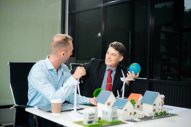 istock Experts collaborate on renewable energy solutions with house models, wind turbines, and solar panels, emphasizing green design 2168992312