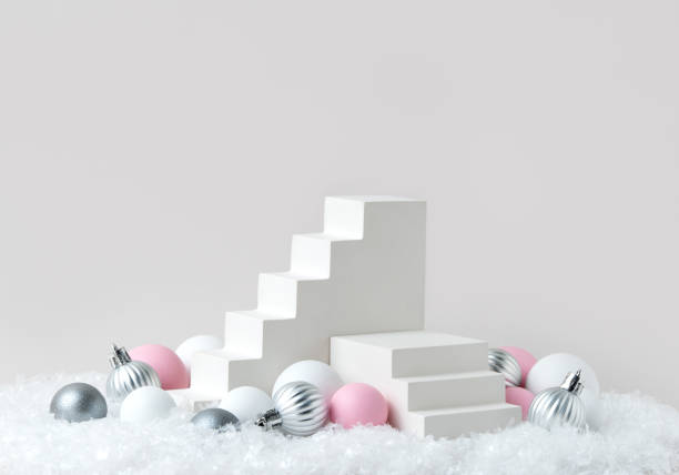 istock Festive Product Presentation Display with White Staircase Props and Pastel Christmas Ornaments on Snowy Background 2168999814