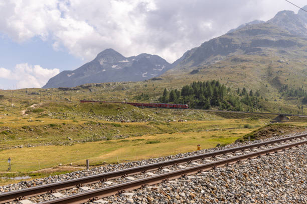 istock Train Crossing a Mountainous Landscape with Railway Tracks in Foreground 2169004335