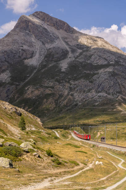 istock Red Train on Curved Track Amidst Mountain Landscape 2169007899