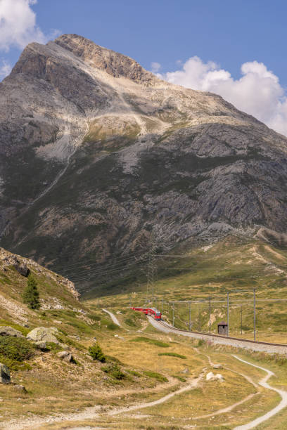 istock Red Train on Curved Track Amidst Mountain Landscape 2169008012