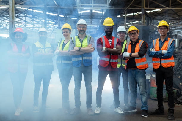 istock Group of various nationalities engineer professional successful team corporate workers standing in factory with smoke. teamwork technician inspector manufacturing industry workplace. 2169012197