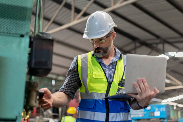 istock Industrial man engineer wear uniform and helmet using laptop are checking system machine at factory. manager technician manufacturing. Workers industrial factory. 2169012335