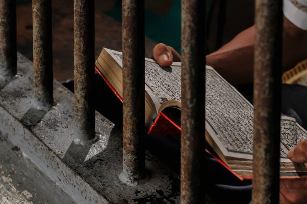 istock priosoner are reading the Koran behind prison rails 2169023513