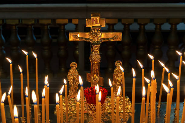 istock Burning prayer candles near a golden crucifix. 2169024749