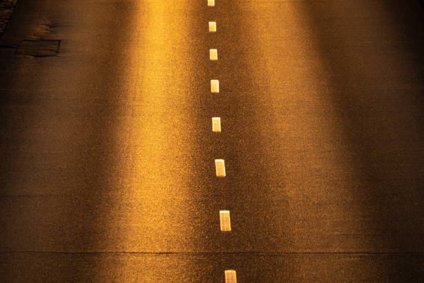 Automobile road filled with yellow sunset light. View from above. Asphalt.