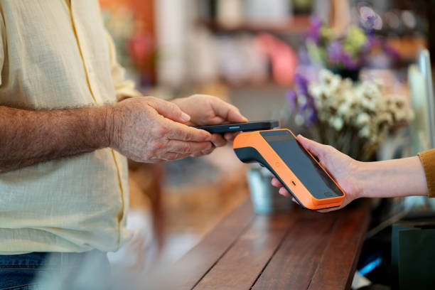 istock Shoppers at a home decor store purchase items using credit cards with contactless technology at the checkout counter. Modern retail experience, where efficiency and convenience meet sustainability. The store owner oversees the transaction. 2169034703