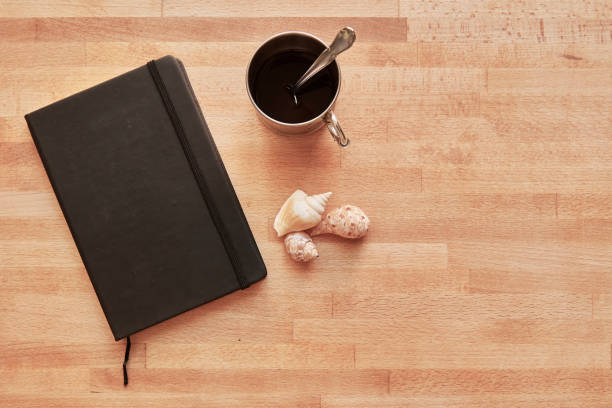 istock Black journal with coffee and seashells on wooden surface with copy space 2169037987