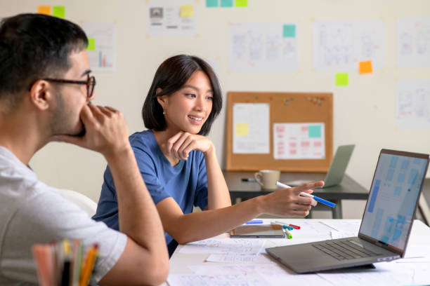 istock UX/UI designers discussing and brainstorming on wireframes for a website and mobile app prototype, surrounded by sketches of user flow and design tools, in the concept of website and mobile application design concept. 2169040301