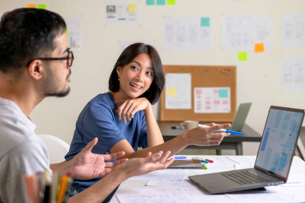 istock UX/UI designers discussing and brainstorming on wireframes for a website and mobile app prototype, surrounded by sketches of user flow and design tools, in the concept of website and mobile application design concept. 2169040309