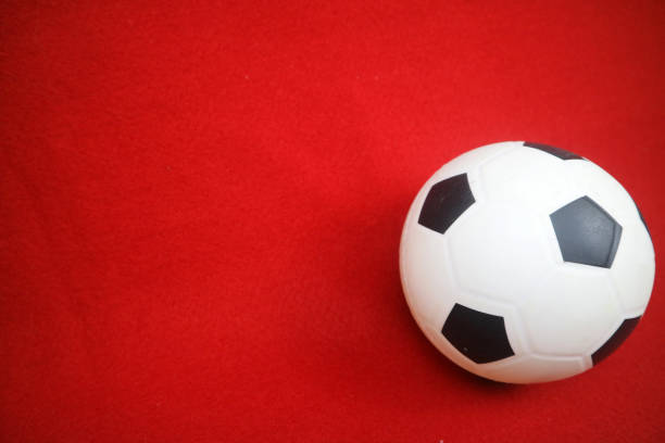istock a small white and black toy rubber ball. Red background 2169047764