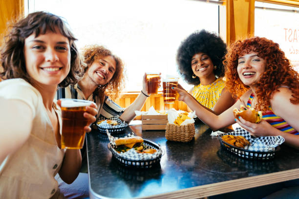 Multiethnic group of friends having meal at diner restaurant Multiethnic group of friends having meal at 80s vintage diner restaurant - Multiracial young people bonding and having fun, eating in an american fast food burger house spanish hamburger stock pictures, royalty-free photos & images
