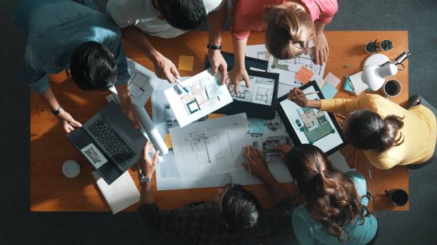 istock Top down of skilled people holding tablet an looking at blueprint. Symposium. 2169060733