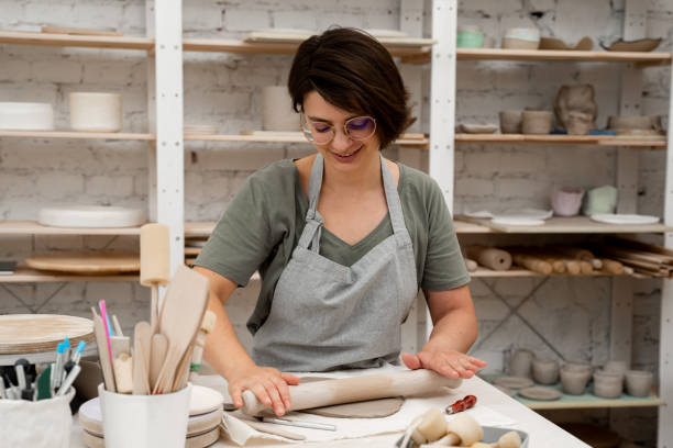 istock Rolling wooden stick to make flat sheet of clay. Preparing clay for cutting and assembling it. Slab building method in ceramics crafting. 2169066028