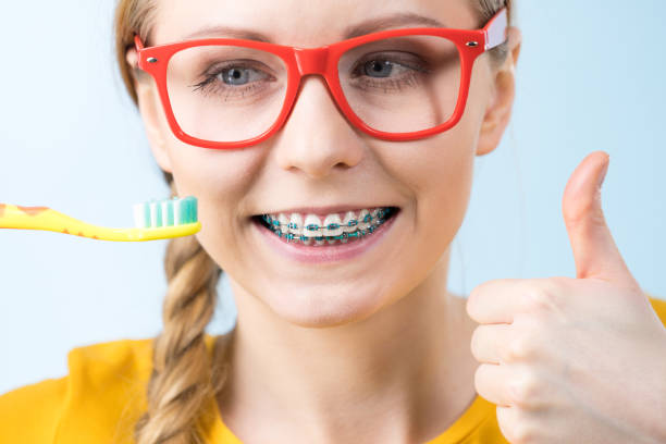 istock Woman smiling cleaning teeth with braces 2169067343