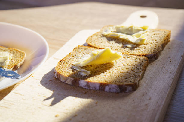 Preparing breakfast meal. Rye bread slices with butter on kitchen table.