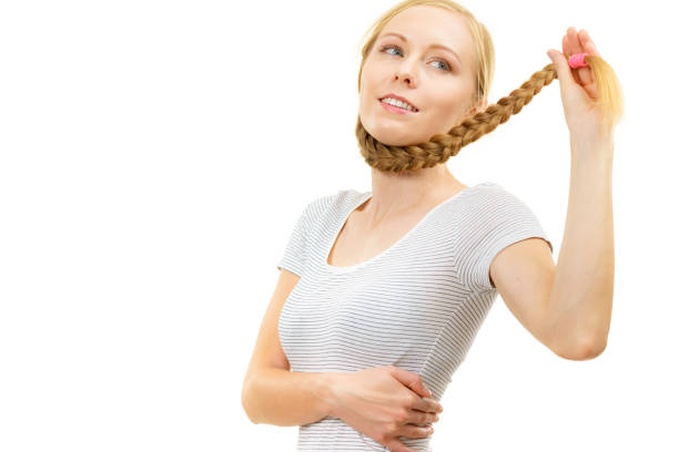 A young Yoruba woman posing for a photo wearing  a Yoruba traditional hairstyle, called Shuku with koroba braids in the front. 'Shuku' translates to 'basket'. The hairstyle consists of cornrows that form at the top of the hair to form a structure that looks like a basket. This hairstyle was traditionally worn by queens and princesses to indicate their royalty. It is a common hairstyle in  modern Nigeria. Photographed in an apartment in Lagos Island, Nigeria.