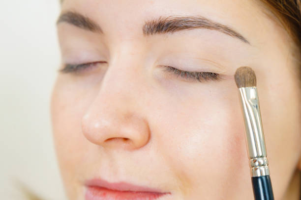 Portrait of lovely Spanish woman powdering her face with brush. Side view of beautiful young woman blushing face with brush. Concept steps of makeup application.