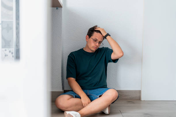 istock Man sitting on the floor with a depressed expression. 2169082088