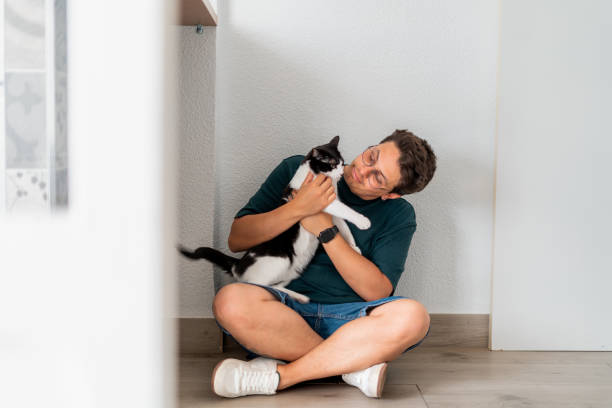 istock Man sitting on the floor playing with his cat 2169082109