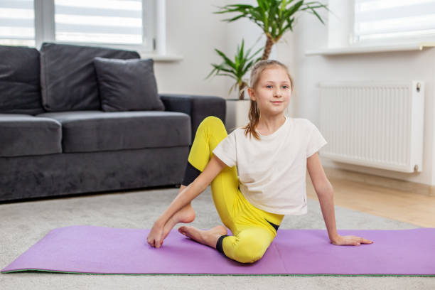 istock Child Practicing Yoga Twist Pose on Mat at Home. Exercise and healthy lifestyle. 2169087882