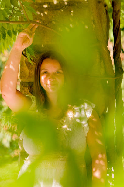 istock woman is posing for a picture in front of a tree 2169088976