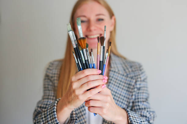 istock girl with paint brushes in her hands. Focus on brushes 2169092822