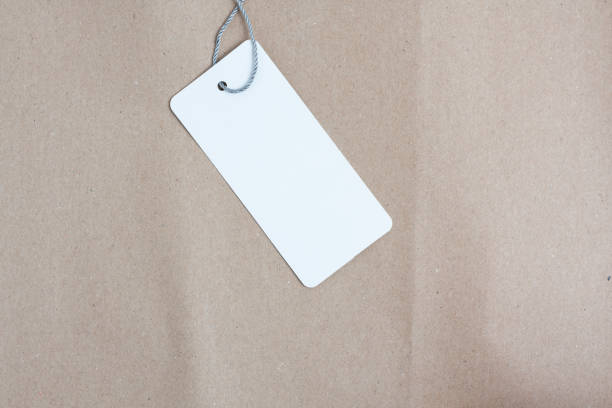 istock Blank white price tag with string on kraft paper background. 2169100849