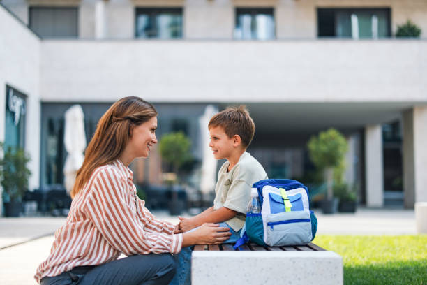 istock Mother and Son Smiling Outside School on First Day Back 2169109374