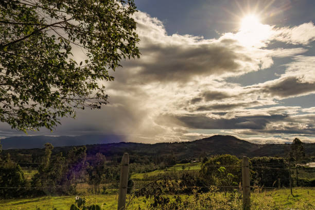 A bright afternoon sun at the edge of a great dark cloud, over the eastern Andean mountains of central Colombia.