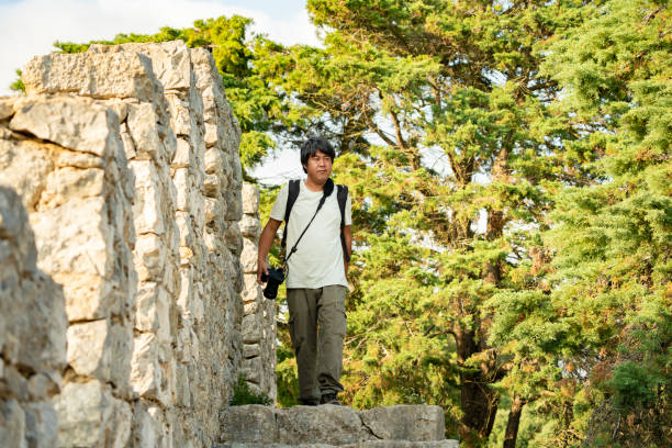 60 year old man with backpack.Window on ancient plain wall sitting admiring.Background blue sky