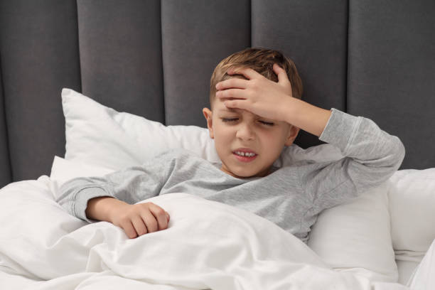 istock Little boy suffering from headache in bed at home 2169129395