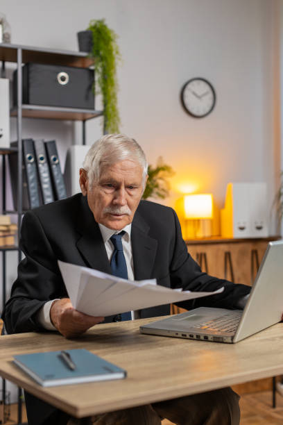 istock Senior businessman working with financial documents and using laptop computer at home office desk 2169130151