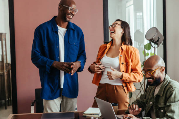 istock Co-workers bonding in a relaxed boardroom meeting, laughing and talking in a modern workspace 2169133484