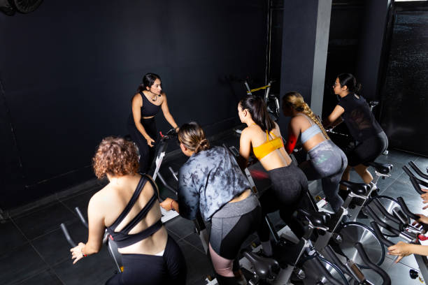 Positive young european female riding exercise bike during cycling class in gym