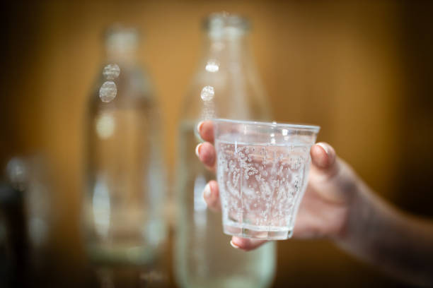 Pouring water into a glass at a cafe. Premium filtered water at a restaurant. Sparkling or still water, soda, mineral water or hydration options drinking from a glass. Close up view.